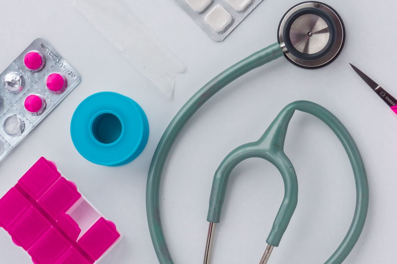 Overhead shot of medical supplies including stethoscope, pills, and scissors.